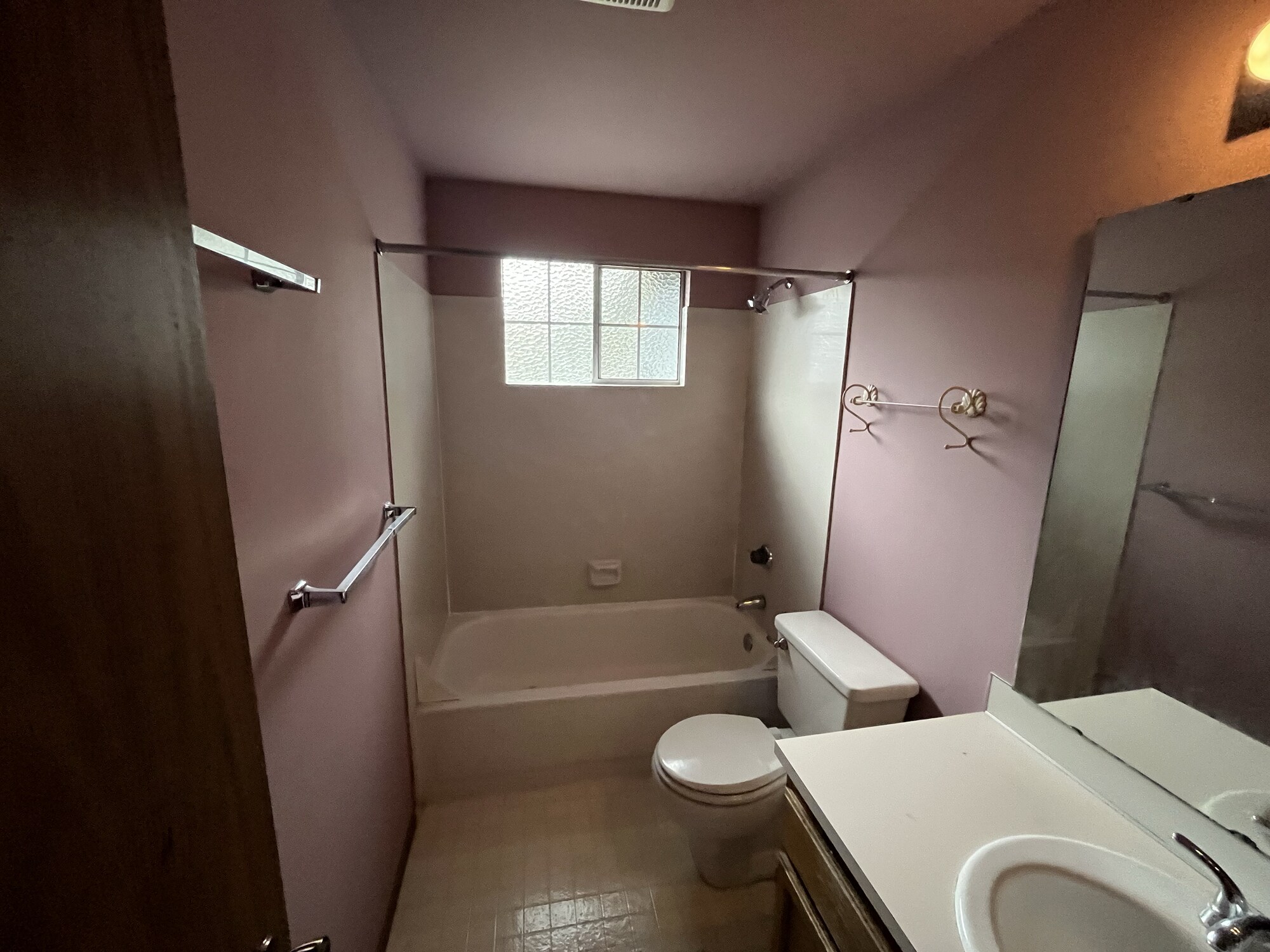 Bathroom before remodel — dated pink walls, old tub surround and tile