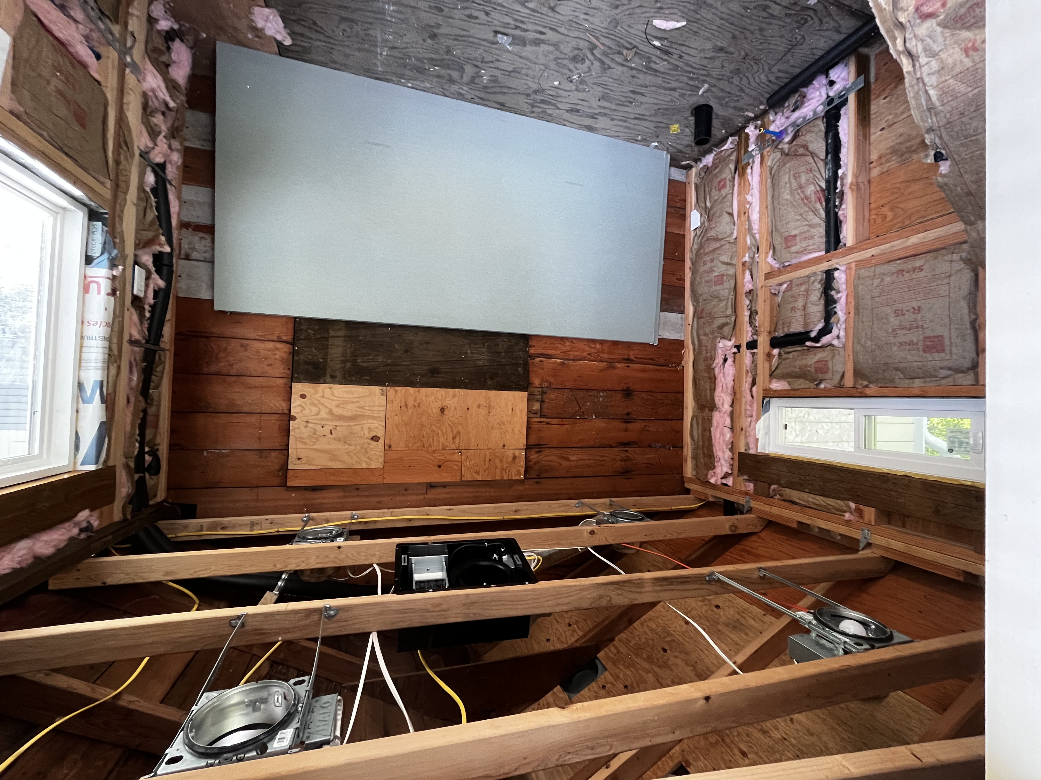 Room before renovation — exposed studs, insulation, and wiring